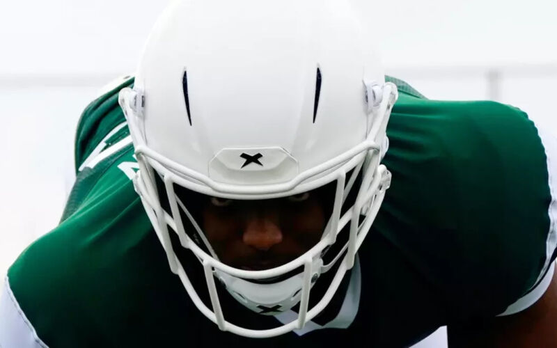 Close up of a football player facing the camera in a three-point stance, wearing the Orbit Pro helmet.